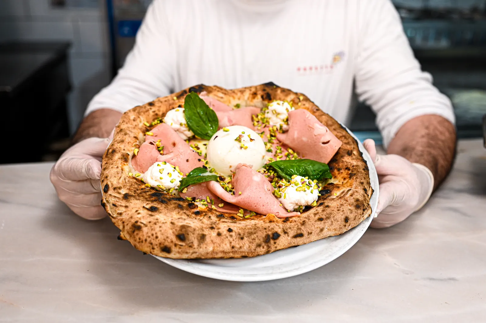 Pizza présentée à la main par le pizzaiolo, restaurant sur le port de Paimpol
